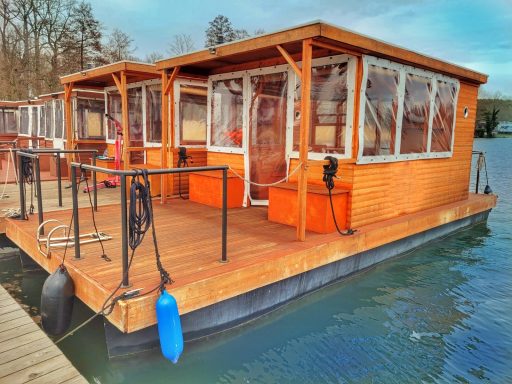 Eine Hausboot-Anlage mit Holzverkleidung, großen Fenstern und orangefarbenen Möbeln.